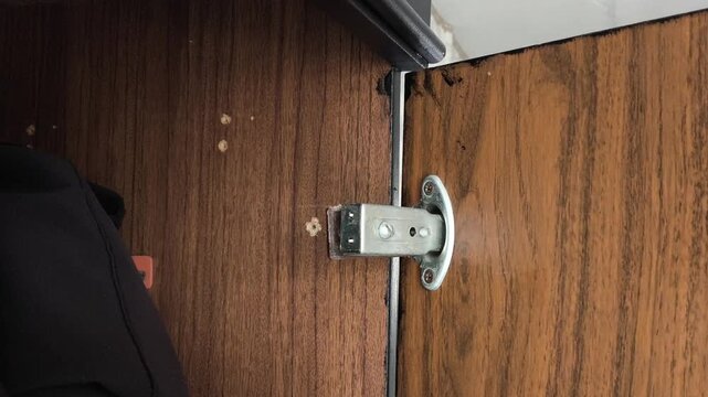 Close-up of a broken close-up of a close-up cabinet door hinge. The cabinet door is hanging