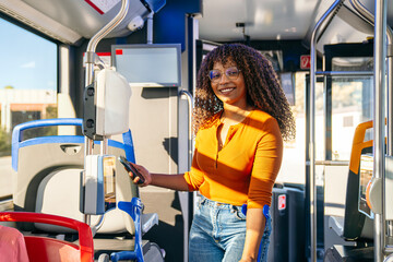 African woman with crutches smiling, paying for public bus transport with smartphone, highlighting urban commuting and disability