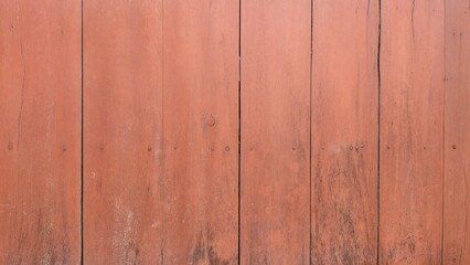 Obraz premium A red wooden surface with natural grain, small cracks, and weathered marks. The warm reddish-brown tones highlight the simple and rustic texture of the wood.