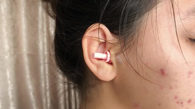 Young brunette girl with earplugs in her ears close-up. Sleep in silence. Protection from noise, noisy neighbors