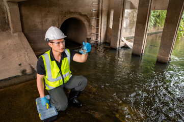 Environmental Scientist Collecting Water Samples Under Bridge for testing
