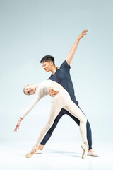Obraz premium Dance Concepts. Loving Couple of Asian Man and Caucasian Woman Performing As Ballet Dancers Over Grey in Studio As Classical Choreography and Ballet Dancing.
