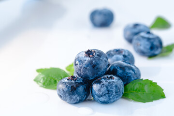 Fresh blueberries of natural color with green leaves on a white background. Forest wet berry close-up
