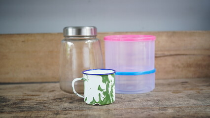 Home kitchen utensils including glass cups and storage jars neatly arranged on a wooden table in natural light