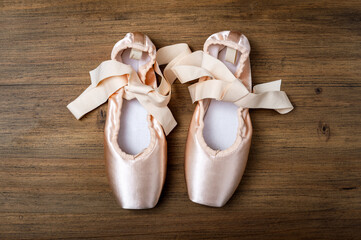 Pink ballet slippers resting on wooden dance floor © photology1971