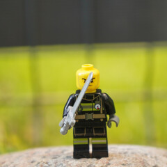 Naklejka premium Lego firefighter minifigure with a sword, ready for action against a blurry green background