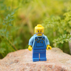 Naklejka premium Lego minifigure of a mechanic standing on a rock with a green background