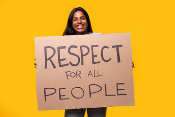 Young woman showing respect for all people holding a sign in studio with yellow background