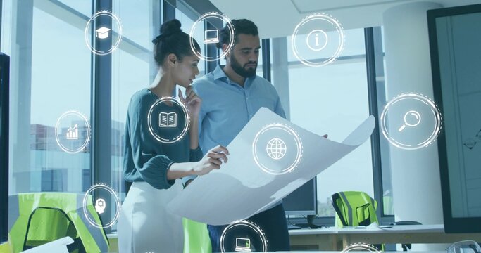 Reviewing blueprint, business casual colleagues working in office with monitors and digital icons