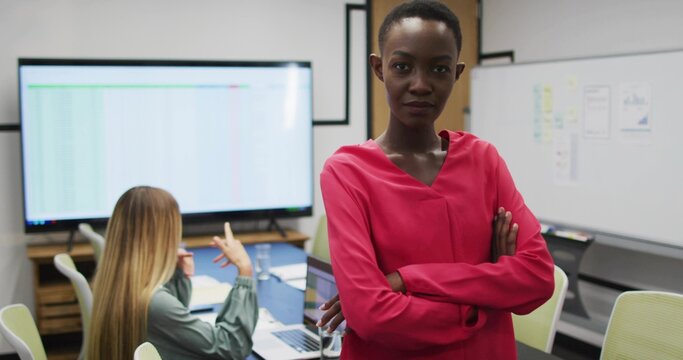 Reviewing figures, woman wearing red blouse crossing arms in office with large display, copy space