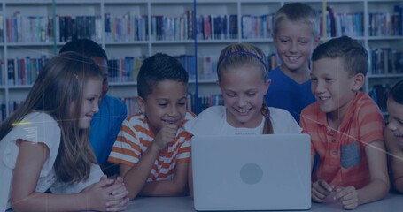 Smiling schoolchildren gathering around laptop in library, with bookshelves backdrop