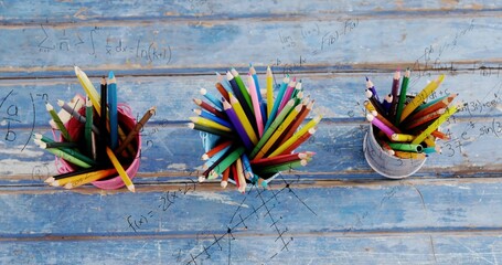 Showing blue cup brimming sharp colored pencils on worn blue table, with math overlay © vectorfusionart