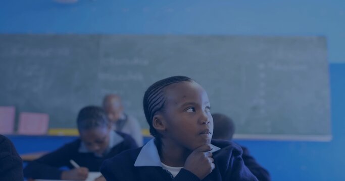 Resting chin on hand uniformed girl gazing to right in classroom, with chalkboard and notebooks