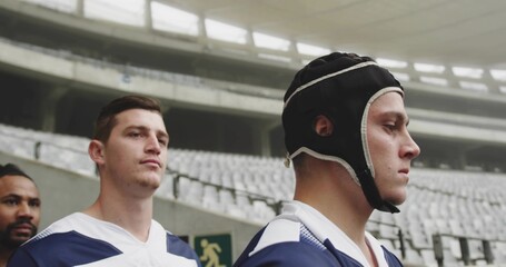 Standing rugby players wearing headgear and blue-white jerseys in tunnel near exit sign, copy space