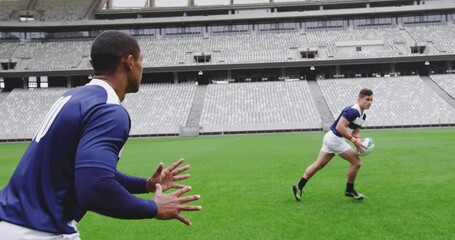 Preparing player wearing navy jersey padded vest on stadium pitch, rugby ball, copy space