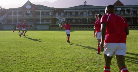 Foreground player wearing red jersey white shorts catching rugby ball at club ground, copy space