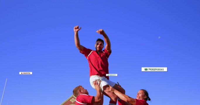 Lifting rugby player by teammates during lineout at pitch by roof, wearing jerseys and cleats