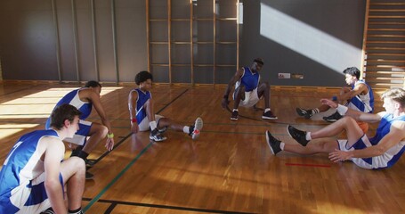 Stretching basketball teammates wearing blue and white uniforms on school court, with climbing bars