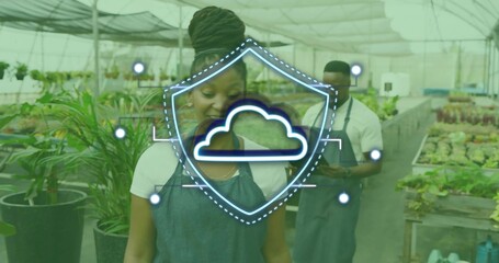 Inspecting nursery worker checking trays in greenhouse, with smartphone and cloud shield overlay