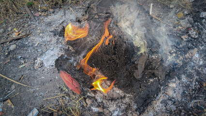 Burning dry trash with flames and smoke outdoors
