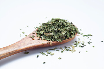 dried and chopped parsley in a wooden spoon