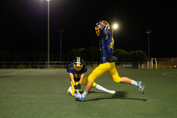 American football players practicing kicking a field goal at night