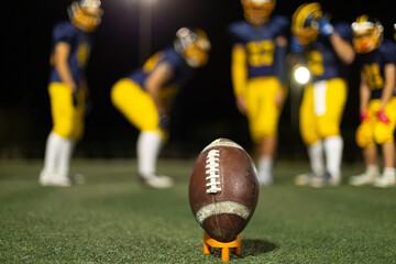 American football ball waiting for kickoff at night game