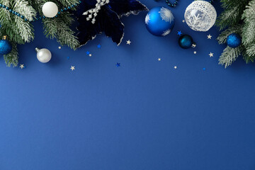 Blue Christmas or winter holiday background with snowy pine branches, baubles, poinsettia and...