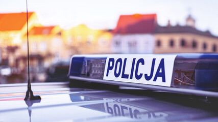 Polish police ("Policja") blue lights panel on top of a patrol car with blurred buildings in the background. © wb77