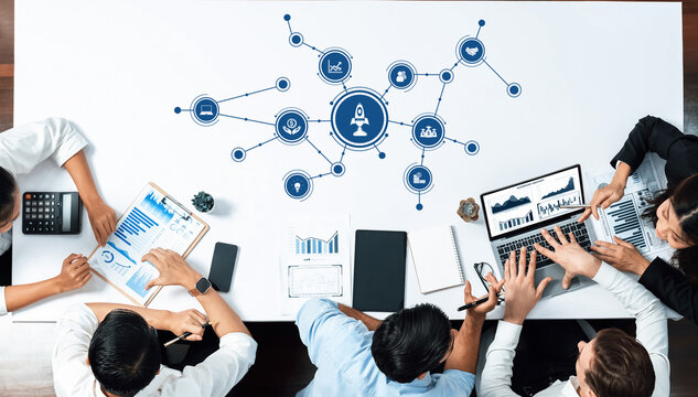 A diverse group of professionals engages in a collaborative business meeting focused on data analysis and strategic planning, surrounded by modern technology and tools. Amity - Powered by Adobe