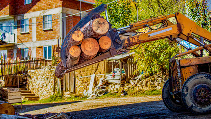 Loader carrying firewood logs in rural village