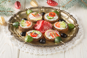 Christmas canapes decoration idea with cream cheese and vegetables close-up in a plate on the table. Horizontal