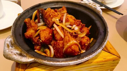 Sizzling hot clay pot dish with tender chicken and onions in savory sauce, perfect for culinary content and restaurant promotions