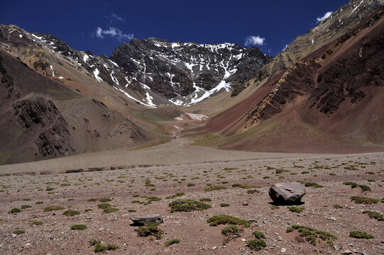 Orange red sand desert, rocky formations and mountains background, blue sky above. Snowy peak against the backdrop of a rocky desert - Powered by Adobe