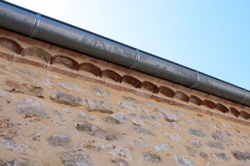 Gouttière en zinc gris sur le mur en pierre