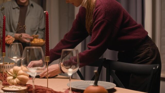 Handheld shot of young diverse man and woman setting home autumn table and communicating at Thanksgiving Day