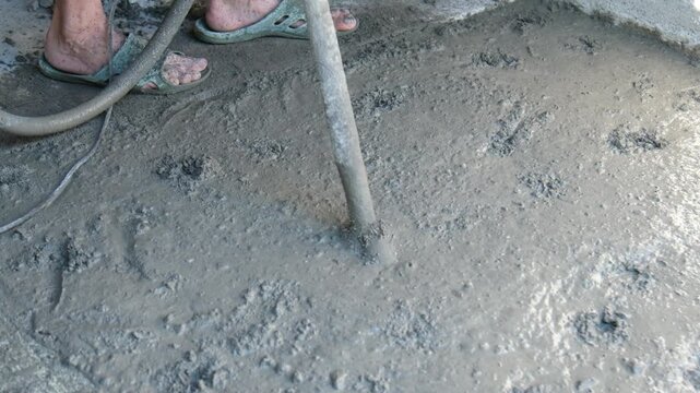 Laying concrete screed and vibrating it with a concrete vibrator. Construction work