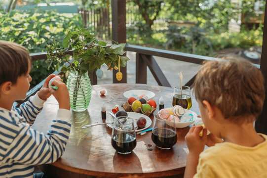 Brothers drawing on easter eggs together at table