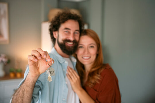 Happy couple holding keys celebrating new home indoors