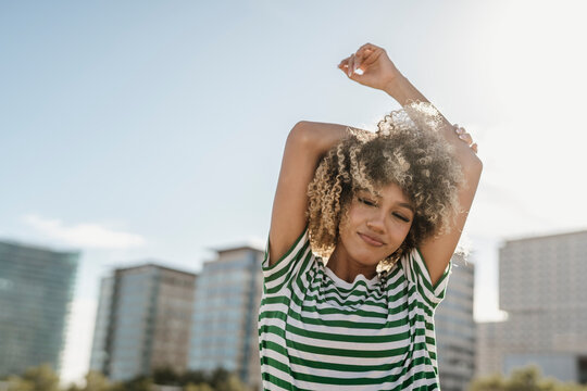Carefree woman with curly hair enjoying leisure time at sunny day