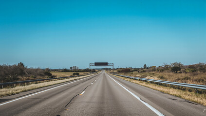 Open road stretches into the distance under a clear blue sky on a sunny day