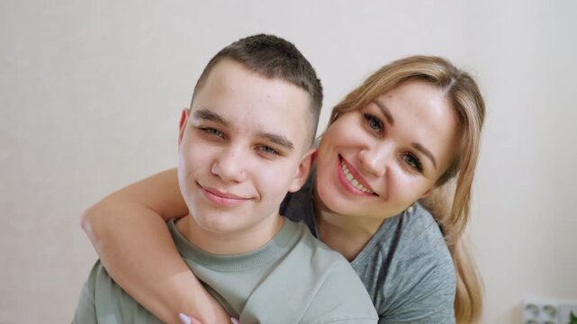 Big sister holding younger brother from behind sharing affectionate moment indoors, both smiling warmly, highlighting bond, love, trust and family connection