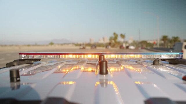 Rear close-up of a police lightbar flashing while driving along a Southern California coastal highway. Lightbar is sharp, background soft and cinematic.