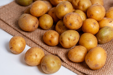 Baby potatoes on a sack bag on a white background