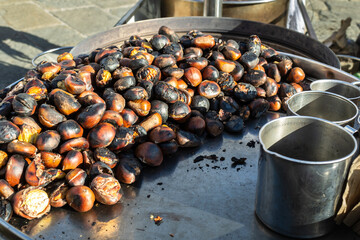 pile of roasted chestnuts on metal tray at street market
