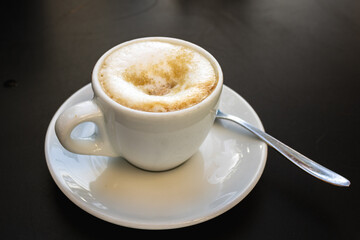cup of cappuccino or latte with frothy milk foam on saucer