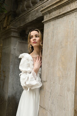figure of beautiful blonde model wearing white fantasy wedding gown.  walking through doorway of...