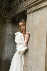 figure of beautiful blonde model wearing white fantasy wedding gown.  walking through doorway of...