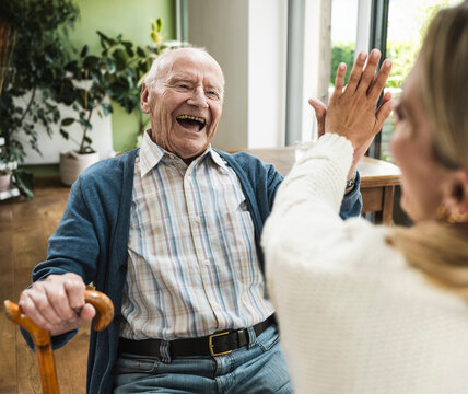 Happy senior man giving high-five to daughter at home