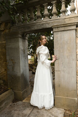 Fototapeta premium Full length female figure of beautiful blonde model wearing white fantasy wedding gown. walking through doorway of historical fairytale castle location 